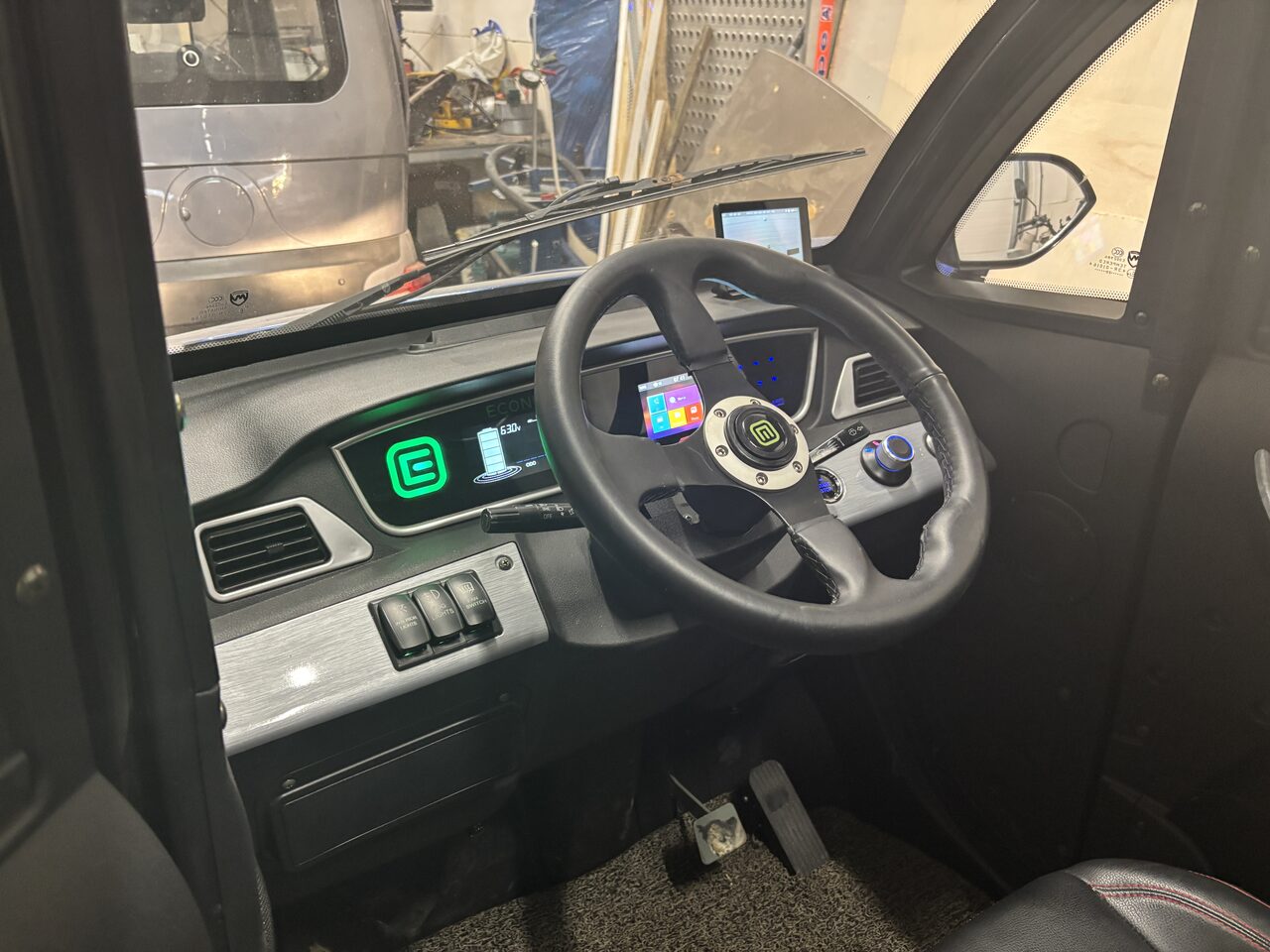 Real Econelo microcar cockpit — Voltron-branded cluster + Android touchscreen running media.