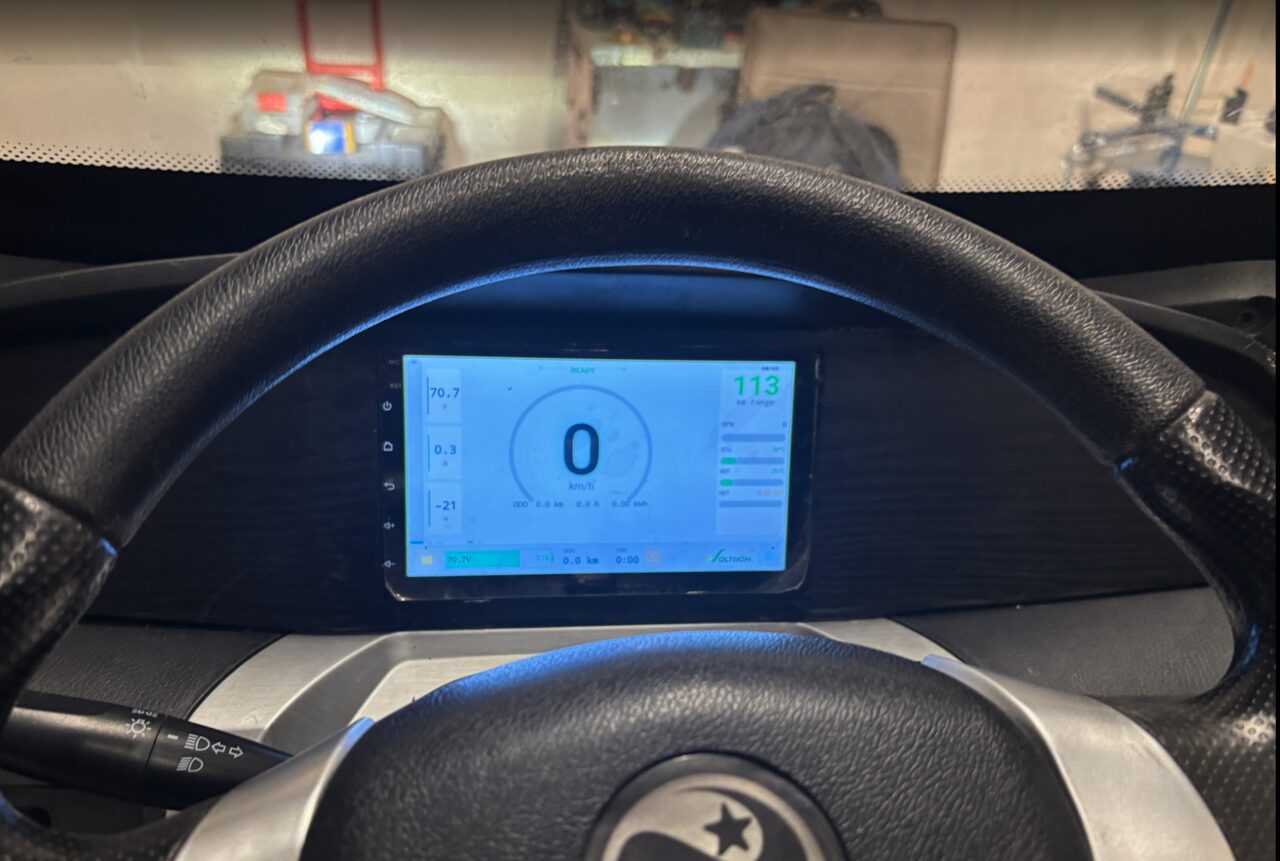 Voltron App running on an in-vehicle automotive tablet — speedometer, battery readings, mode indicator and live status.