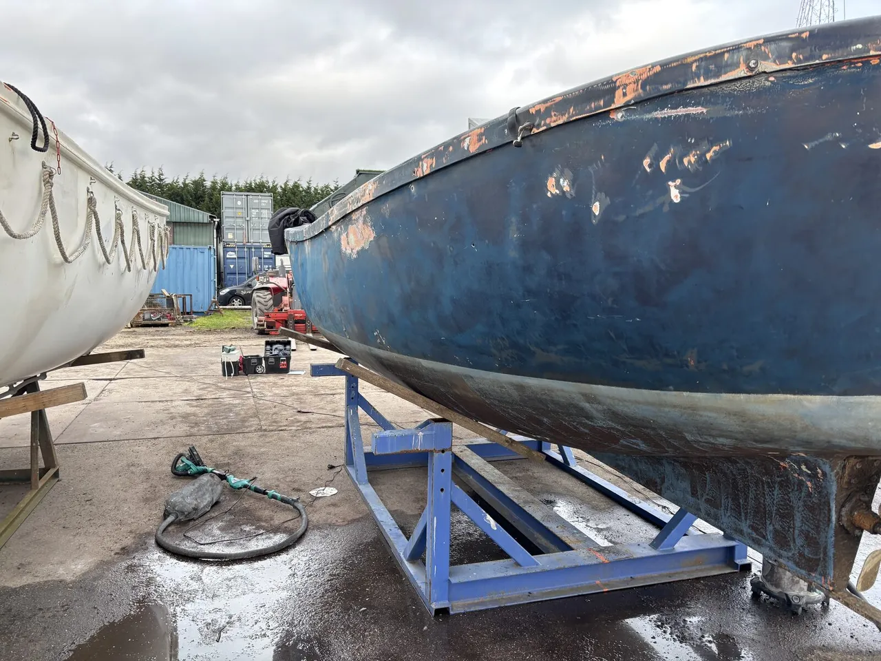 BEFORE — weathered hull on the stand, rust streaks and peeling paint